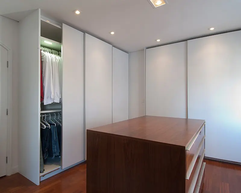 Closet com portas brancas de correr e ilha central de madeira