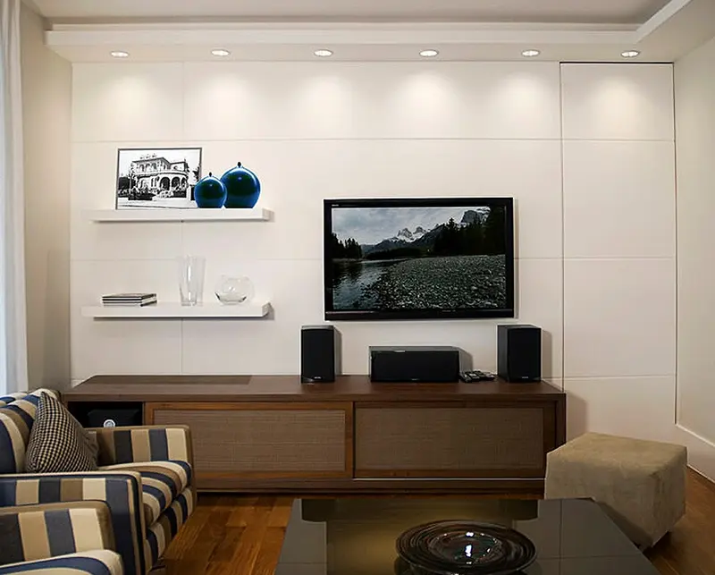 Sala com rack de madeira, painel claro e prateleiras